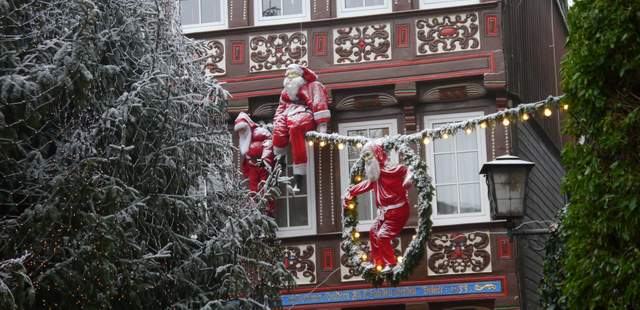 Weihnachtsmänner hängen an Häuserwand in Goslar bei Teamevent Dekoration an Häuserwand mit Lichterkette und Weihnachtsmännern