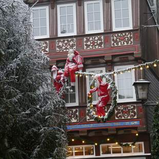 Weihnachtsmänner hängen an Häuserwand in Goslar bei Teamevent Dekoration an Häuserwand mit Lichterkette und Weihnachtsmännern