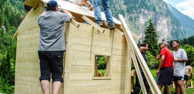 Team montiert das Dach einer Holzhütte im Außenbereich