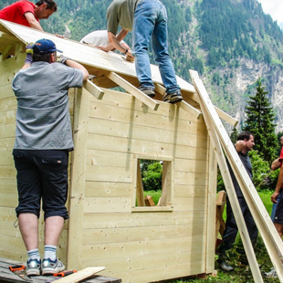 Team montiert das Dach einer Holzhütte im Außenbereich