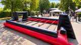 Human Kicker Eventmodul im aufgebauten Zustand Aufgebauter Human Kicker in rot und schwarz bei einem Firmenevent im Außenbereich