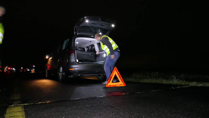 Fahrzeug mit offener Heckklappe im Dunkeln mit Warndreieck