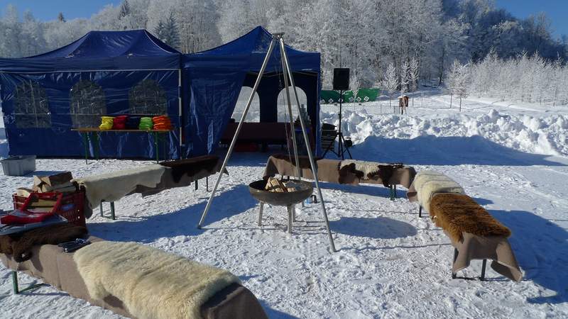 Basecamp mit Lagerfeuer, Bänken mit Fellen und Cateringzelt