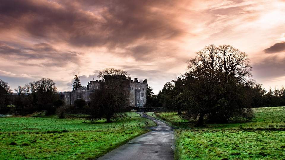 Weg zwischen grünen Wiesen zu einem irisches Schloss in der Landschaft