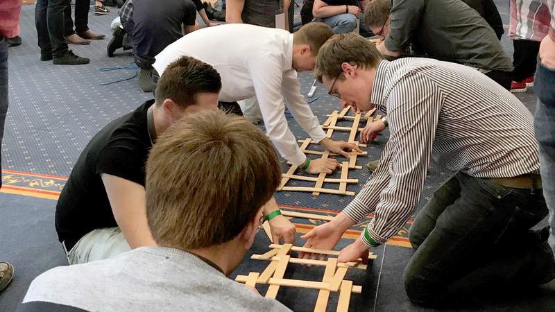 Vier Teilnehmer bauen eine Leonardobrücke als Teamevent
