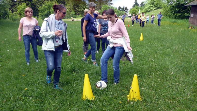 Frau schießt Fußball durch zwei Pylonen beim Fun Golf