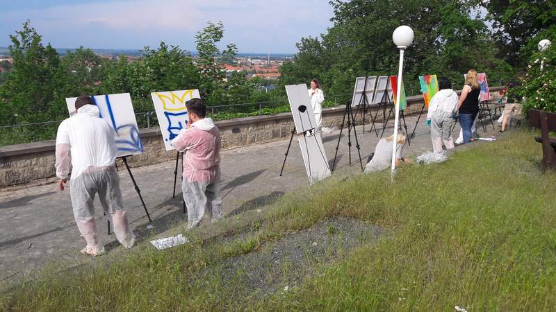 Mehrere Personen die auf Leinwänden sprayen