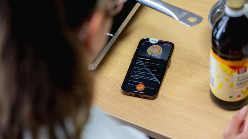 Teilnehmerin folgt der digitalen Schritt-für-Schritt Kochanleitung auf der Mundet-App während eines Teamevents