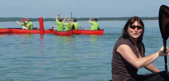 Birgit Fischer sitzt im Kanu auf dem Wasser. Im Hintergrund sieht man mehrere Kanus.