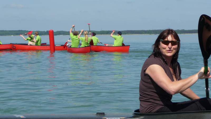 Birgit Fischer sitzt im Kanu auf dem Wasser. Im Hintergrund sieht man mehrere Kanus.