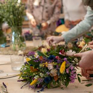 Fokus auf die präzise Handarbeit beim Binden eines farbenfrohen Kranzes im StraightCurls Workshop.
