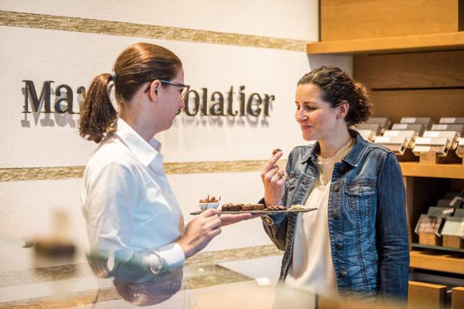 Eine Dame kostet Schweizer Schokolade beim Chocolatier