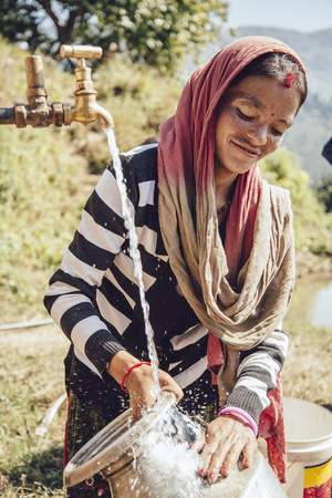 Eine junge Frau wäscht in Nepal Geschirr