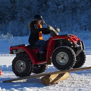Quadparcours im Winter Quad-Fahrerin passiert eine übergroße Wippe