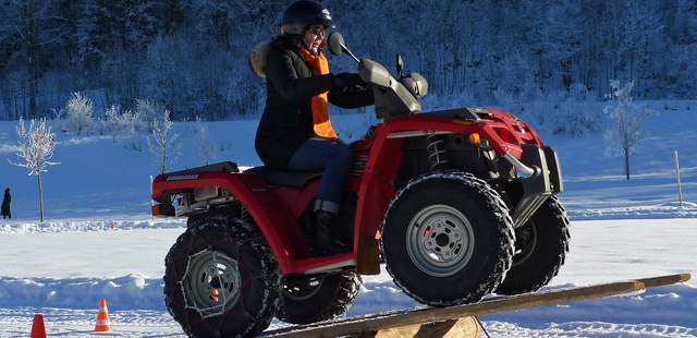 Quadparcours im Winter Quad-Fahrerin passiert eine übergroße Wippe