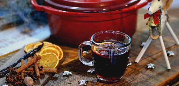 roter Topf mit Glühwein, Orangen und Zimtstangen