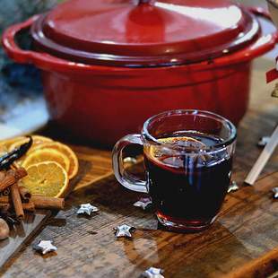 roter Topf mit Glühwein, Orangen und Zimtstangen