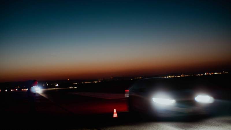 Auto von vorn im Dunkeln bremst an roten Pylonen