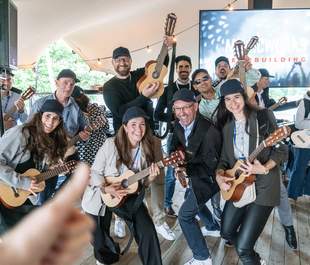 Teilnehmende spielen kleine Gitarren, Gitalelen, bei einem Teamevent, das ohne Vorkenntnisse gemeinsames Musizieren, Teambuilding und Interaktion ermöglicht.