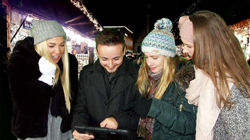 Teilnehmer auf dem Weihnachtsmarkt spielen eine City Rallye