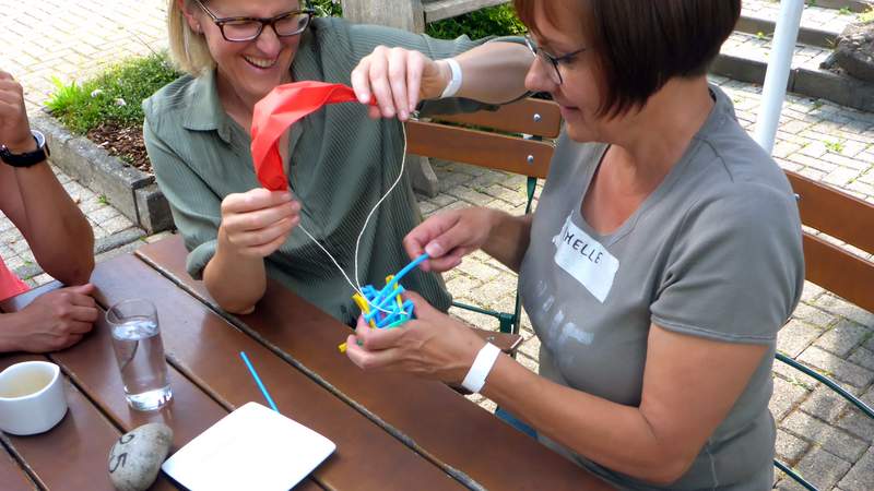 Zwei Frauen verpacken ein Ei bei Teamaktion Eierfall im Rahmen eines Firmenevents