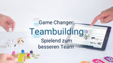 Das Bild zeigt einen weißen Tisch mit Spielutensilien: Eine Hand stapelt Würfel zu einer Pyramide, Spielplättchen mit Meeple-Figuren, ein Tablet mit dem Serious Game "Eternal Ice" und Spielkarten am unteren Bildrand.