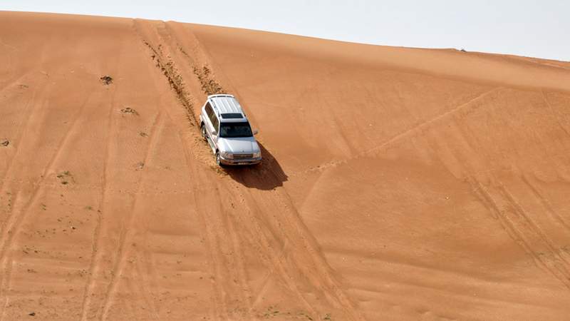 Ein weißer Jeep fährt durch die arabische Sandwüste 