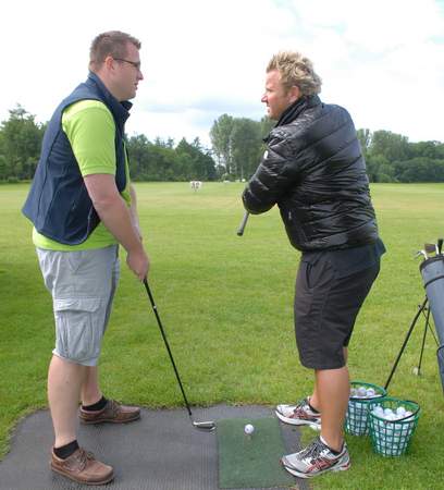 Adi Hengstberger zeigt einem Gast den richtigen Schwung des Golfschlägers.