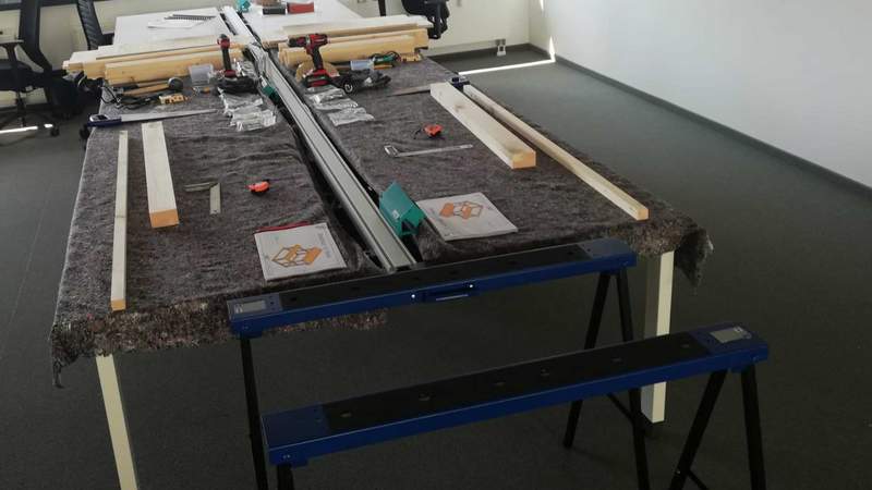 Arbeitstische mit vorgerferigten Holzteilen, Werkzeugen und Arbeitsplan