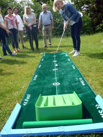 Frau beim Hole in One auf dem rasen beim Betriebsausflug inklusive Fun Golf