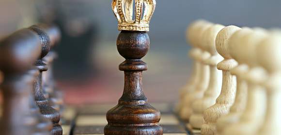 Einer Bauerfigur aus einem Schachspiel mit Krone auf dem Kopf