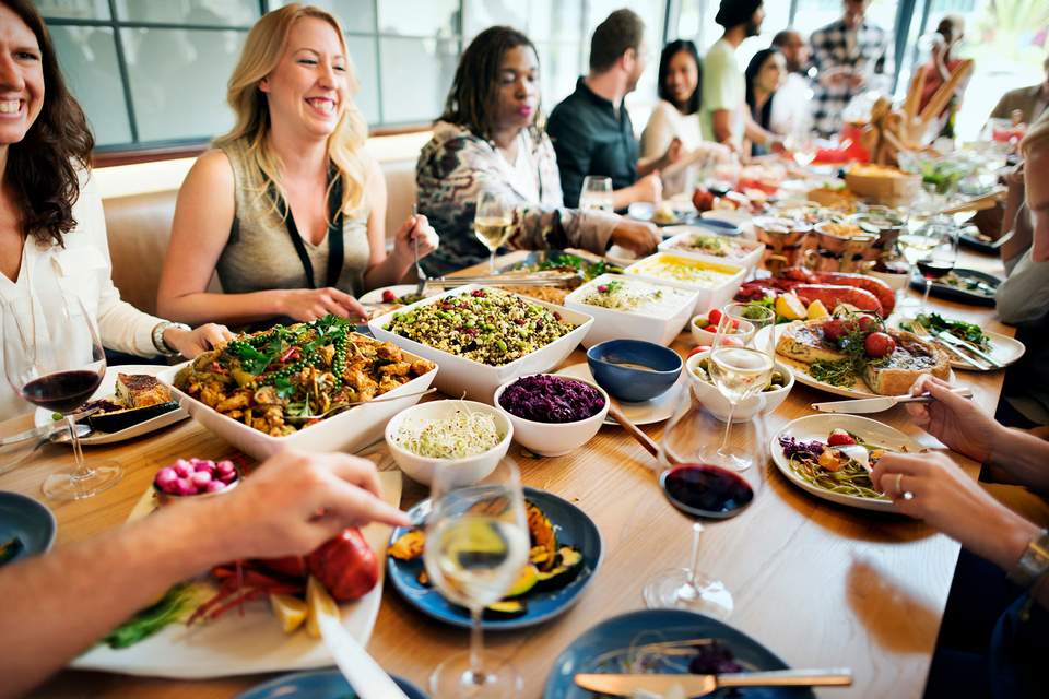 Teamkochen und Team-Essen beim Teamevent Menschen sitzen am Tisch in fröhlicher Runde und essen gemeinsam.