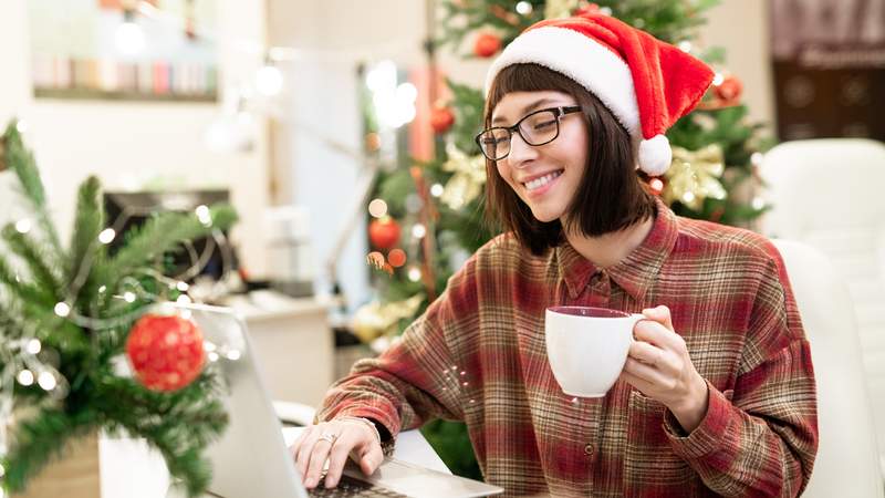 Eine Person am Laptop trinkt einen Glühwein