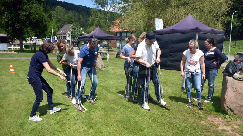 Frau unterstützt Kollegen im Team-Ski beim Teamvent LaserPowerBiathlon