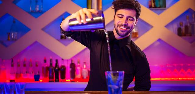 Junger Mann mixt einen Cocktail