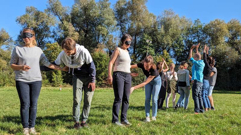 Teilnehmern mit Augenbinden wird beim "Moorpfad" geholfen