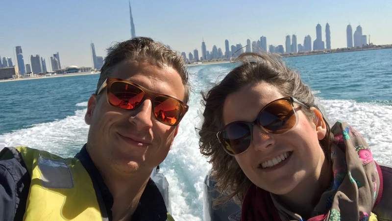 Zwei Personen mit Schwimmweste sitzen im Speedboot vor Dubais Skyline