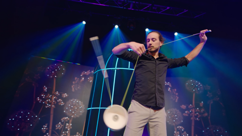 Das Bild zeigt einen Diabolo Künstler, wie er konzentriert einen Trick vorführt