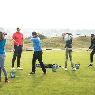 Golf Schnupperkurs in idyllischer Natur: Trainer und Teilnehmer beim Abschlag auf dem sonnigen Golfplatz, umgeben von saftigem Grün und einem malerischen Waldpanorama. Aktion, Spaß und Lernen im Freien – Golfbegeisterung in vollen Zügen!