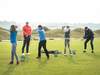 Golf Schnupperkurs in idyllischer Natur: Trainer und Teilnehmer beim Abschlag auf dem sonnigen Golfplatz, umgeben von saftigem Grün und einem malerischen Waldpanorama. Aktion, Spaß und Lernen im Freien – Golfbegeisterung in vollen Zügen!