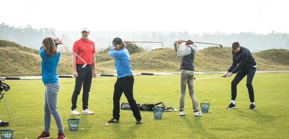 Golf Schnupperkurs in idyllischer Natur: Trainer und Teilnehmer beim Abschlag auf dem sonnigen Golfplatz, umgeben von saftigem Grün und einem malerischen Waldpanorama. Aktion, Spaß und Lernen im Freien – Golfbegeisterung in vollen Zügen!