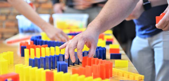 Teilnehmer platzieren Dominosteine beim kreativen Teambuilding Event