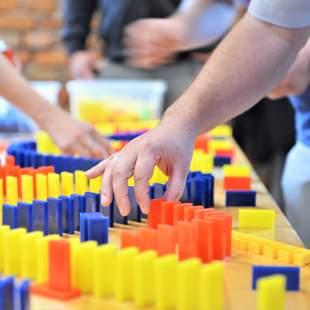 Teilnehmer platzieren Dominosteine beim kreativen Teambuilding Event