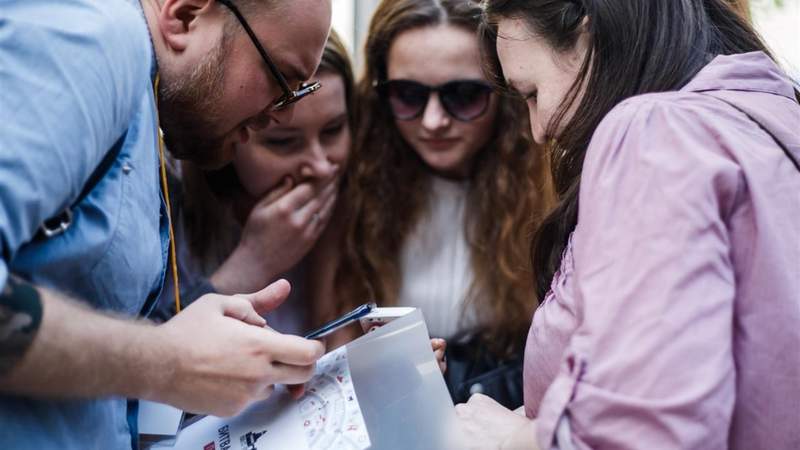 4 junge Menschen schauen in einen Stadtplan und besprechen die weitere Vorgehensweise bei der KGB-Tour