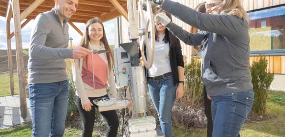 Personen bedienen gemeinsam den Plasticpreneur Extrudor