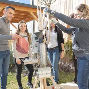 Personen bedienen gemeinsam den Plasticpreneur Extrudor