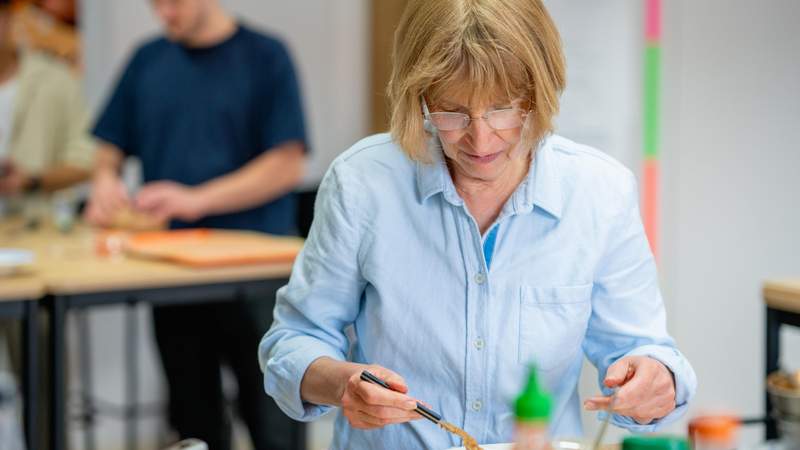 Teilnehmerin bereitet konzentriert und sorgfältig ein Gericht beim Mundet-App Team-Kochevent zu