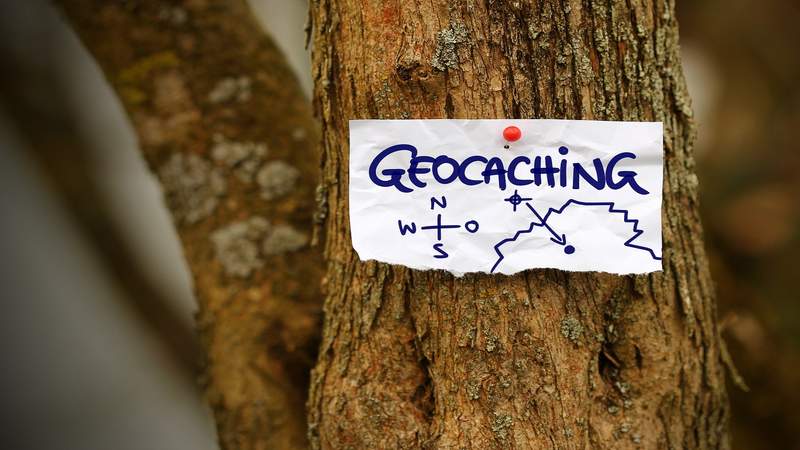 Ein Zettel auf dem Geocaching steht, an einen Baum gepinnt
