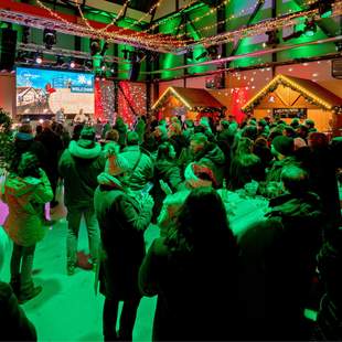 Indoor-Weihnachtsmarkt mit Gästen, weihnachtlichen Hütten und gemütlicher Dekoration
