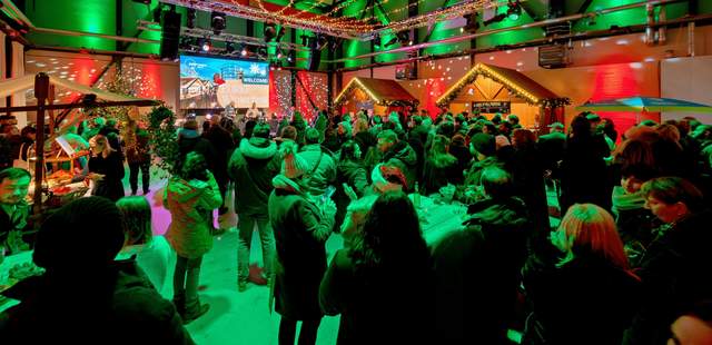 Indoor-Weihnachtsmarkt auf dem EUREF-Campus Berlin Indoor-Weihnachtsmarkt mit Gästen, weihnachtlichen Hütten und gemütlicher Dekoration